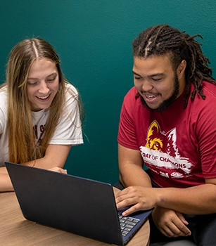 Two students working on a laptop