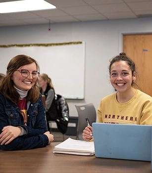 Seated students smile in class